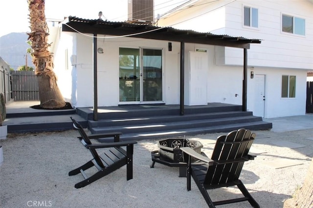 rear view of house featuring a fire pit, a patio, fence, and stucco siding