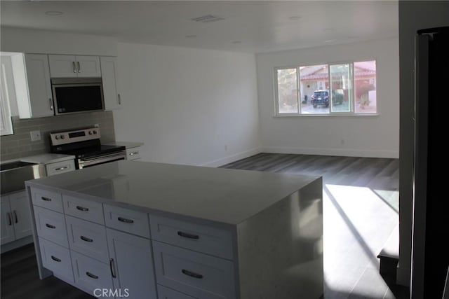 kitchen with stainless steel appliances, tasteful backsplash, visible vents, white cabinets, and a kitchen island