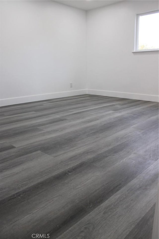 unfurnished room featuring dark wood-style flooring and baseboards