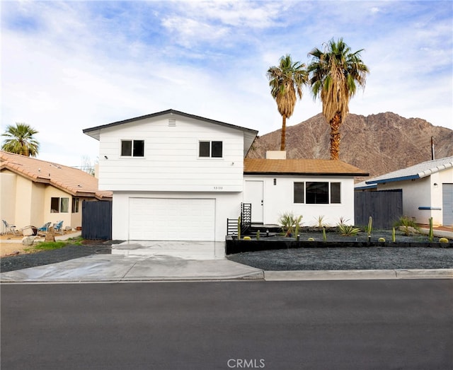 split level home with driveway, an attached garage, fence, and a mountain view