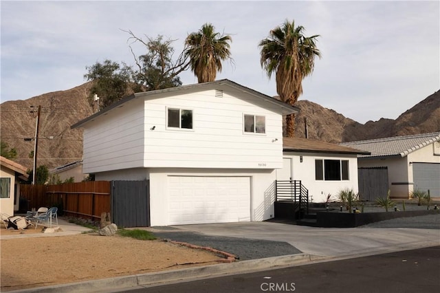 split level home with a garage, fence, a mountain view, and stucco siding