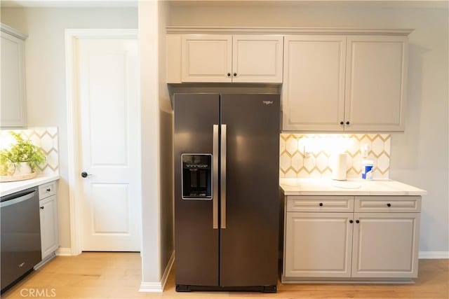 kitchen with stainless steel appliances, white cabinetry, backsplash, and light hardwood / wood-style floors