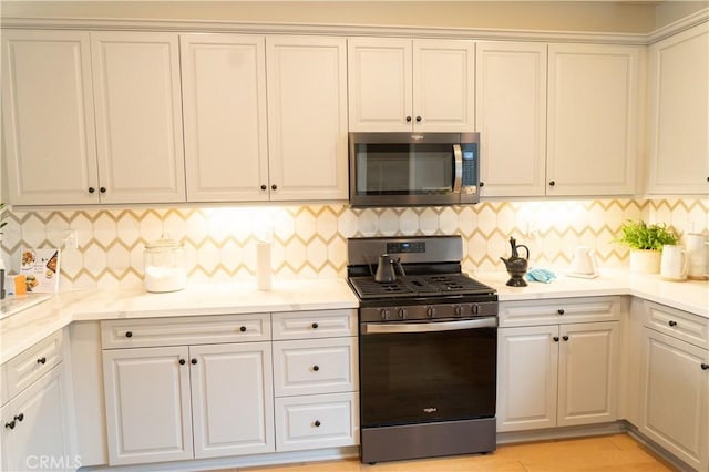 kitchen featuring backsplash, appliances with stainless steel finishes, and white cabinets