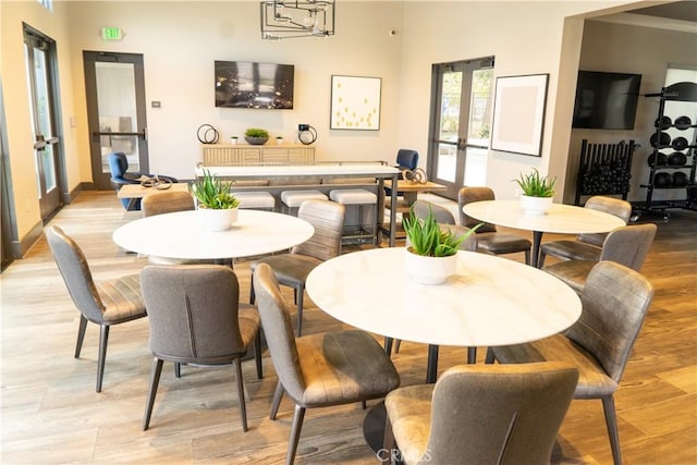 dining area with an inviting chandelier, light hardwood / wood-style floors, and french doors