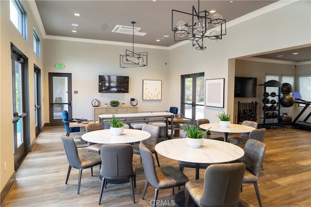 dining room featuring ornamental molding, light hardwood / wood-style floors, french doors, and a high ceiling