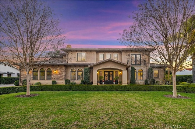 mediterranean / spanish-style home with a front yard, a chimney, and stucco siding