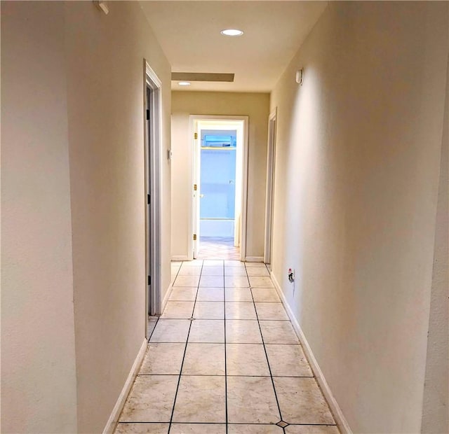 hallway with recessed lighting, light tile patterned flooring, and baseboards