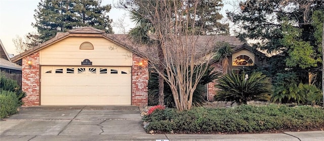 view of front of home with a garage, concrete driveway, and brick siding