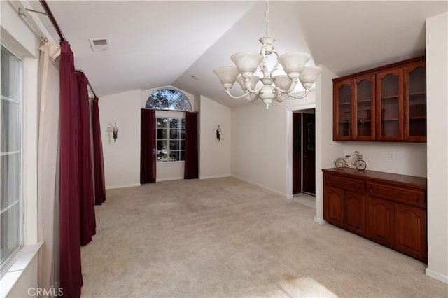 unfurnished dining area featuring a notable chandelier, light colored carpet, visible vents, baseboards, and vaulted ceiling