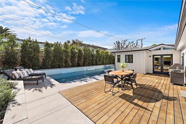 wooden deck with a fenced in pool, french doors, and a grill