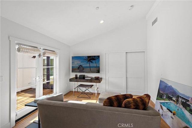 living room featuring vaulted ceiling, light hardwood / wood-style floors, and french doors