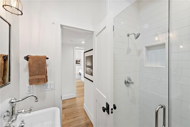 bathroom with a shower with door, hardwood / wood-style flooring, and sink