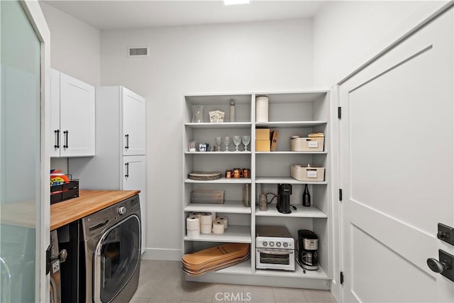 clothes washing area featuring cabinets and washer / dryer