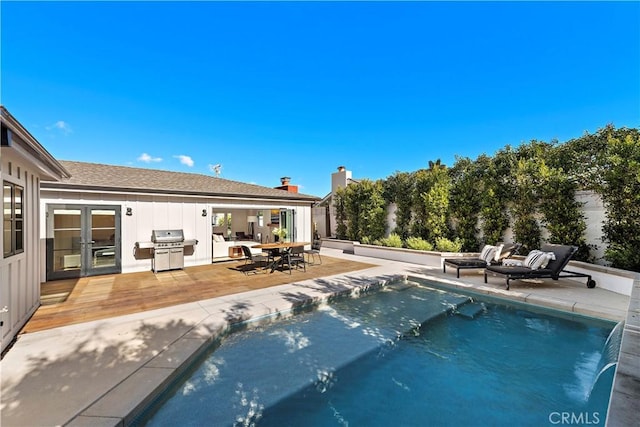 view of pool featuring french doors, grilling area, and a deck