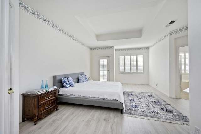 bedroom featuring a raised ceiling and light wood-type flooring