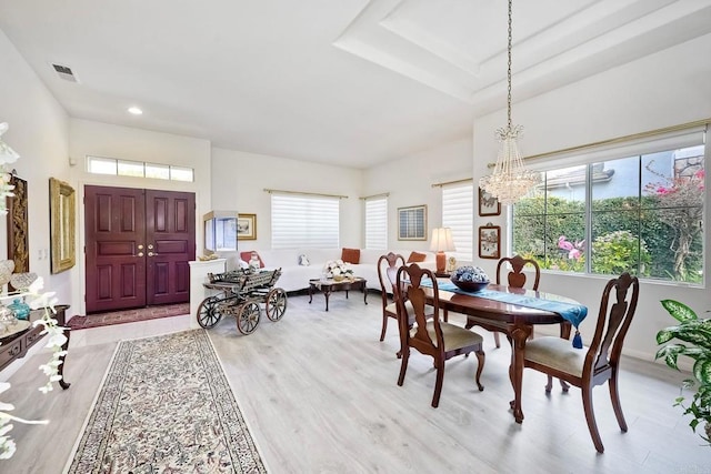 dining space featuring a tray ceiling, light hardwood / wood-style floors, and a chandelier