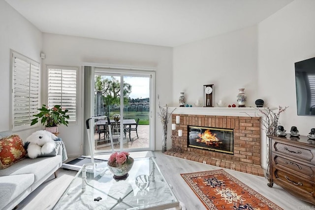 living room with a brick fireplace and hardwood / wood-style floors