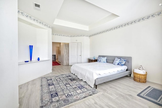 bedroom with a raised ceiling and hardwood / wood-style floors