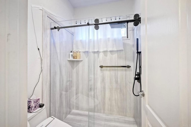 bathroom with a shower with door and toilet