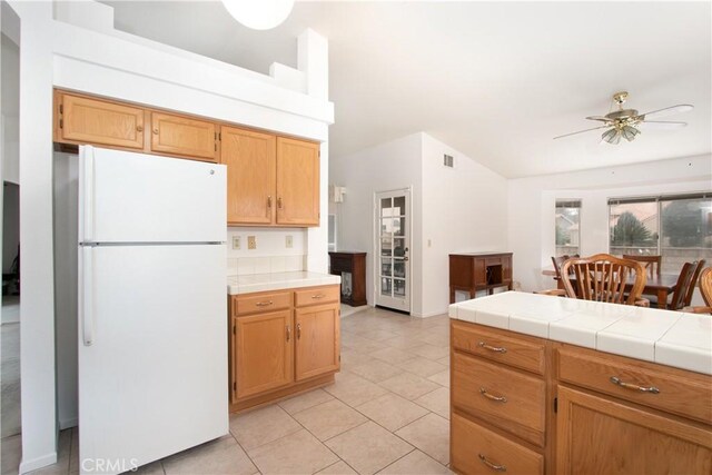 2869 Maple Dr, Hemet, CA 92545 - kitchen featuring freestanding refrigerator, light tile patterned flooring, a ceiling fan, tile countertops, and vaulted ceiling