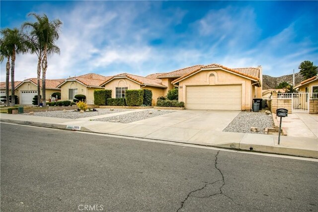 2869 Maple Dr, Hemet, CA 92545 - view of front of home featuring a garage, driveway, a tiled roof, a gate, and stucco siding
