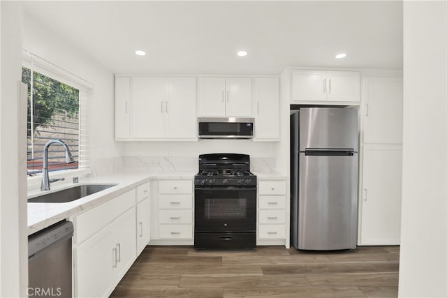 kitchen featuring sink, stainless steel appliances, dark hardwood / wood-style floors, light stone countertops, and white cabinets