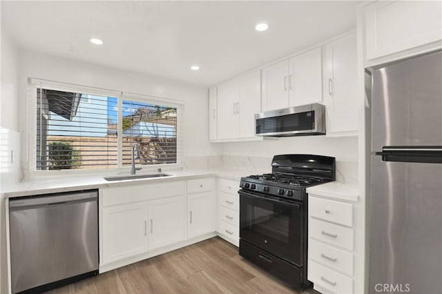 kitchen featuring stainless steel appliances, white cabinetry, sink, and light wood-type flooring