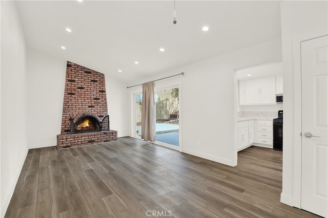 unfurnished living room with a fireplace, dark hardwood / wood-style flooring, and vaulted ceiling