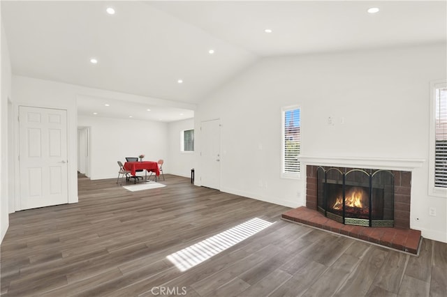 unfurnished living room featuring a brick fireplace, dark wood-type flooring, and vaulted ceiling