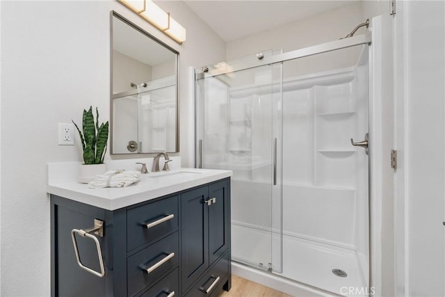 bathroom featuring vanity, a shower with shower door, and wood-type flooring