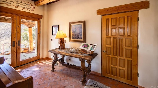 doorway featuring brick floor, baseboards, beam ceiling, and french doors