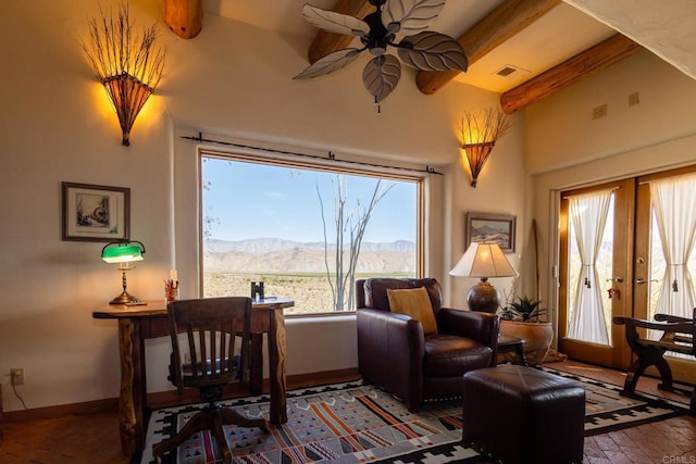 sitting room featuring baseboards, ceiling fan, beamed ceiling, brick floor, and a mountain view