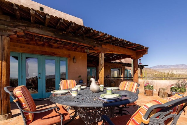 view of patio / terrace with outdoor dining space, french doors, and a mountain view