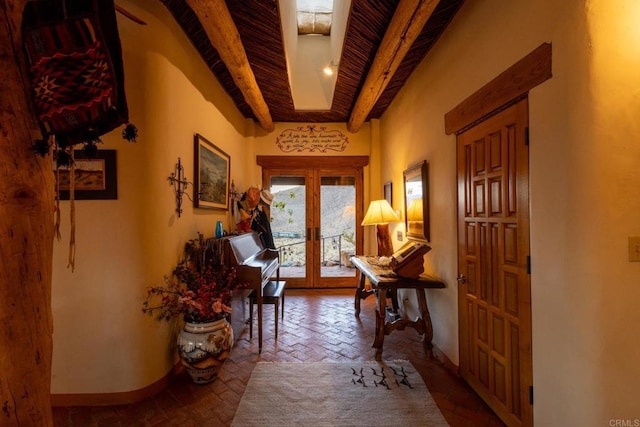 foyer entrance with brick floor, a skylight, beam ceiling, french doors, and baseboards