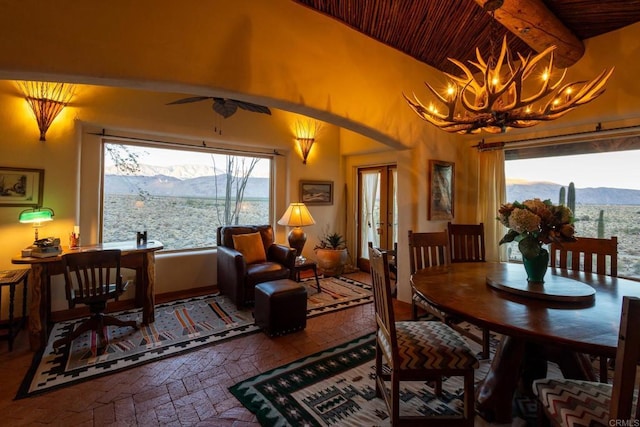 dining space featuring wooden ceiling, beam ceiling, brick floor, and a mountain view