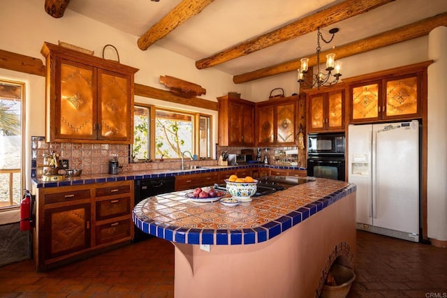 kitchen featuring black appliances, tasteful backsplash, a kitchen island, and tile counters