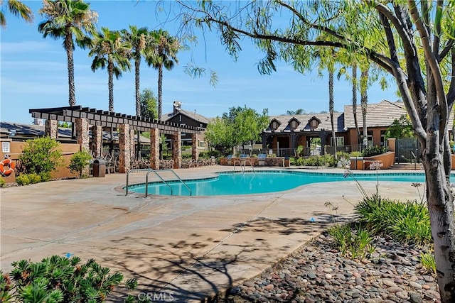 community pool with a patio, fence, and a pergola