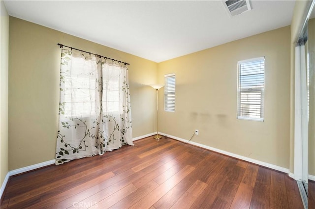 spare room featuring wood-type flooring, baseboards, and visible vents