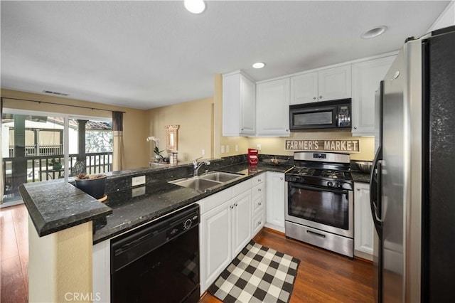 kitchen with visible vents, black appliances, a sink, white cabinetry, and a peninsula