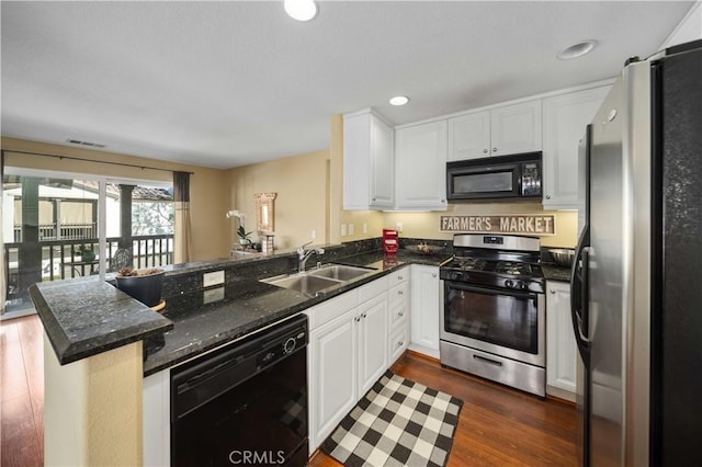 kitchen featuring visible vents, a sink, a peninsula, black appliances, and white cabinetry