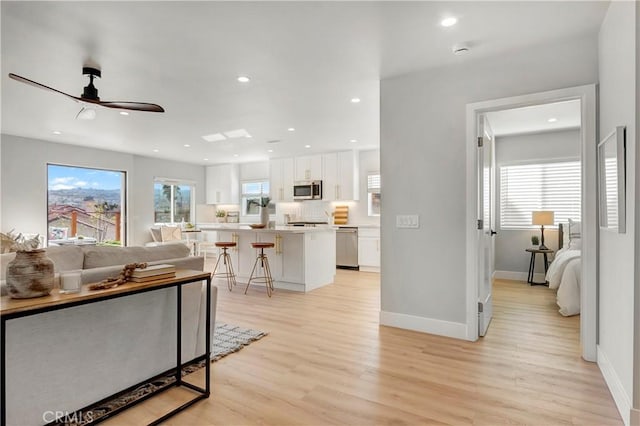 living room with light hardwood / wood-style floors and ceiling fan