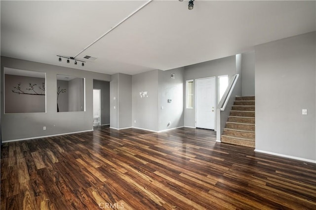 unfurnished living room featuring rail lighting and dark hardwood / wood-style flooring