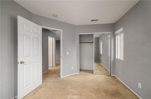 unfurnished bedroom featuring light colored carpet and a closet