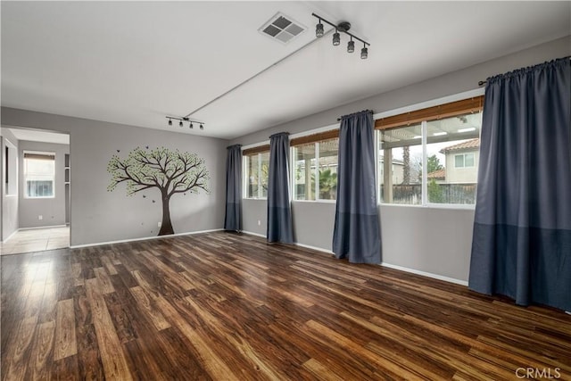 unfurnished room featuring track lighting, dark hardwood / wood-style floors, and a healthy amount of sunlight