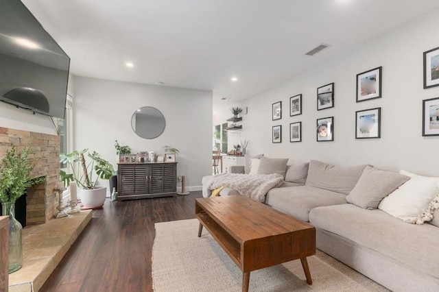 living room with a stone fireplace and dark hardwood / wood-style floors