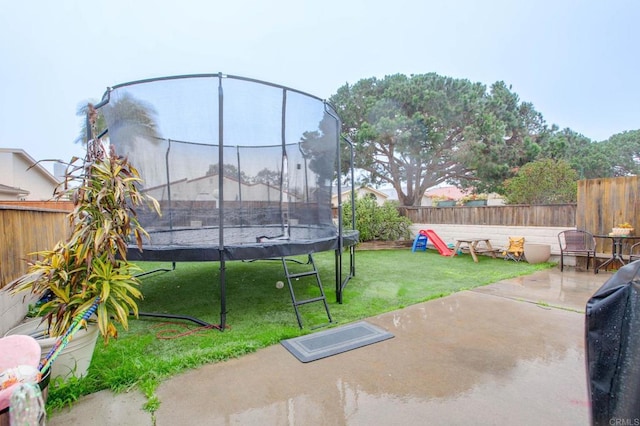 view of yard with a trampoline and a patio