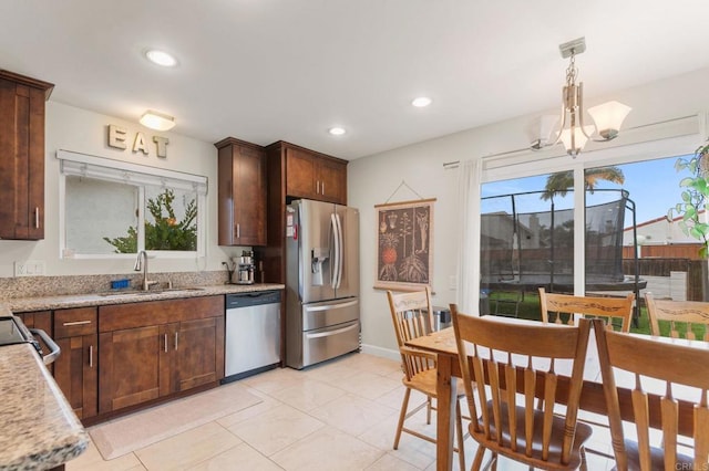 kitchen with light stone countertops, appliances with stainless steel finishes, a healthy amount of sunlight, and decorative light fixtures