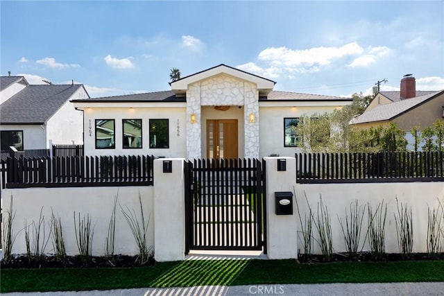 bungalow-style house featuring a gate, a fenced front yard, stone siding, and stucco siding