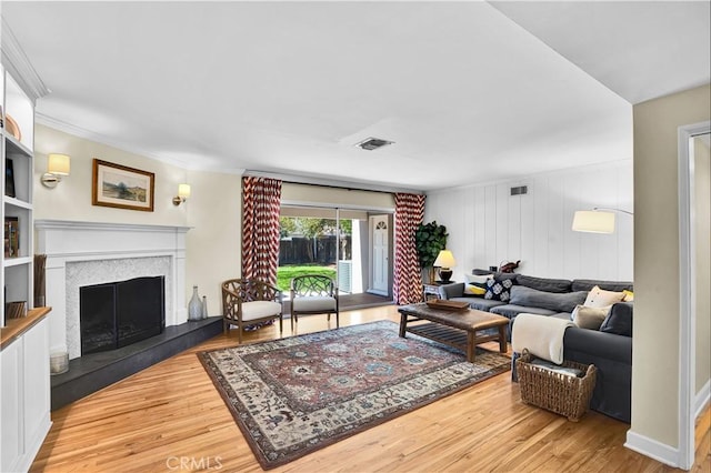 living area featuring baseboards, visible vents, a fireplace with raised hearth, and wood finished floors