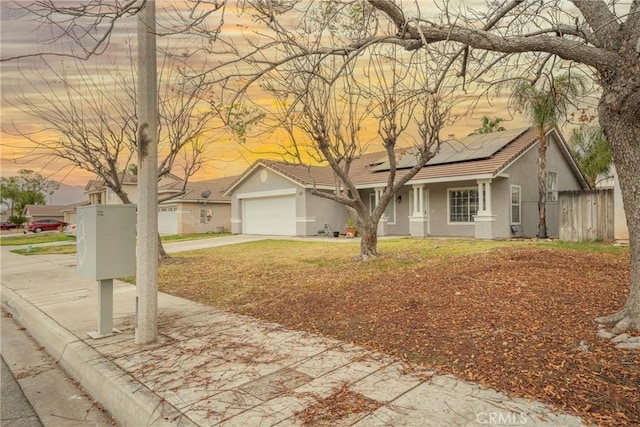 ranch-style house featuring a garage and solar panels